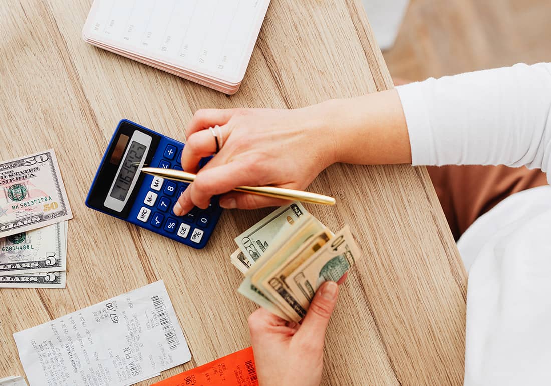 Person Holding Money while working on Calculator